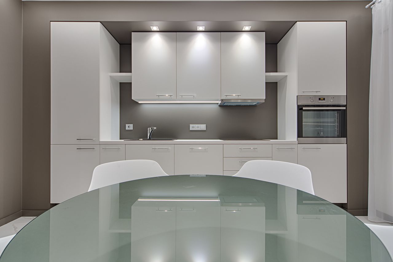 Contemporary kitchen space with minimalist white cabinets and stylish glass table