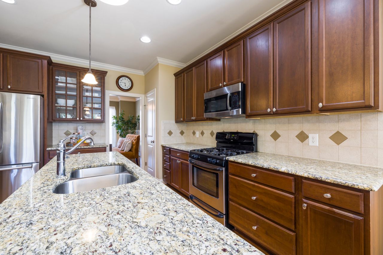 Spacious modern kitchen featuring wooden cabinets, granite countertops, and stainless steel appliances